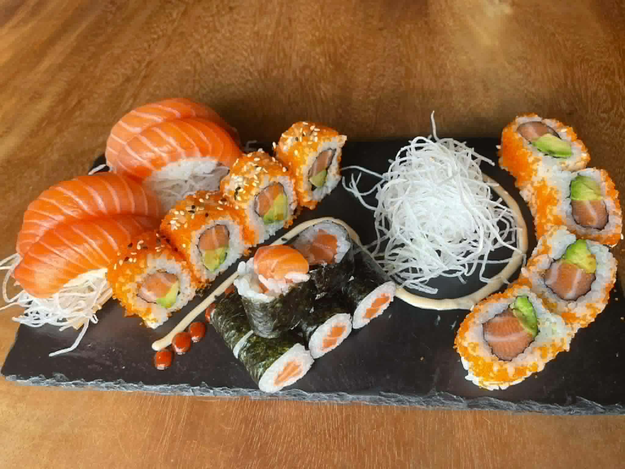 Große Auswahl an Sushirollen auf einem Holzschiff